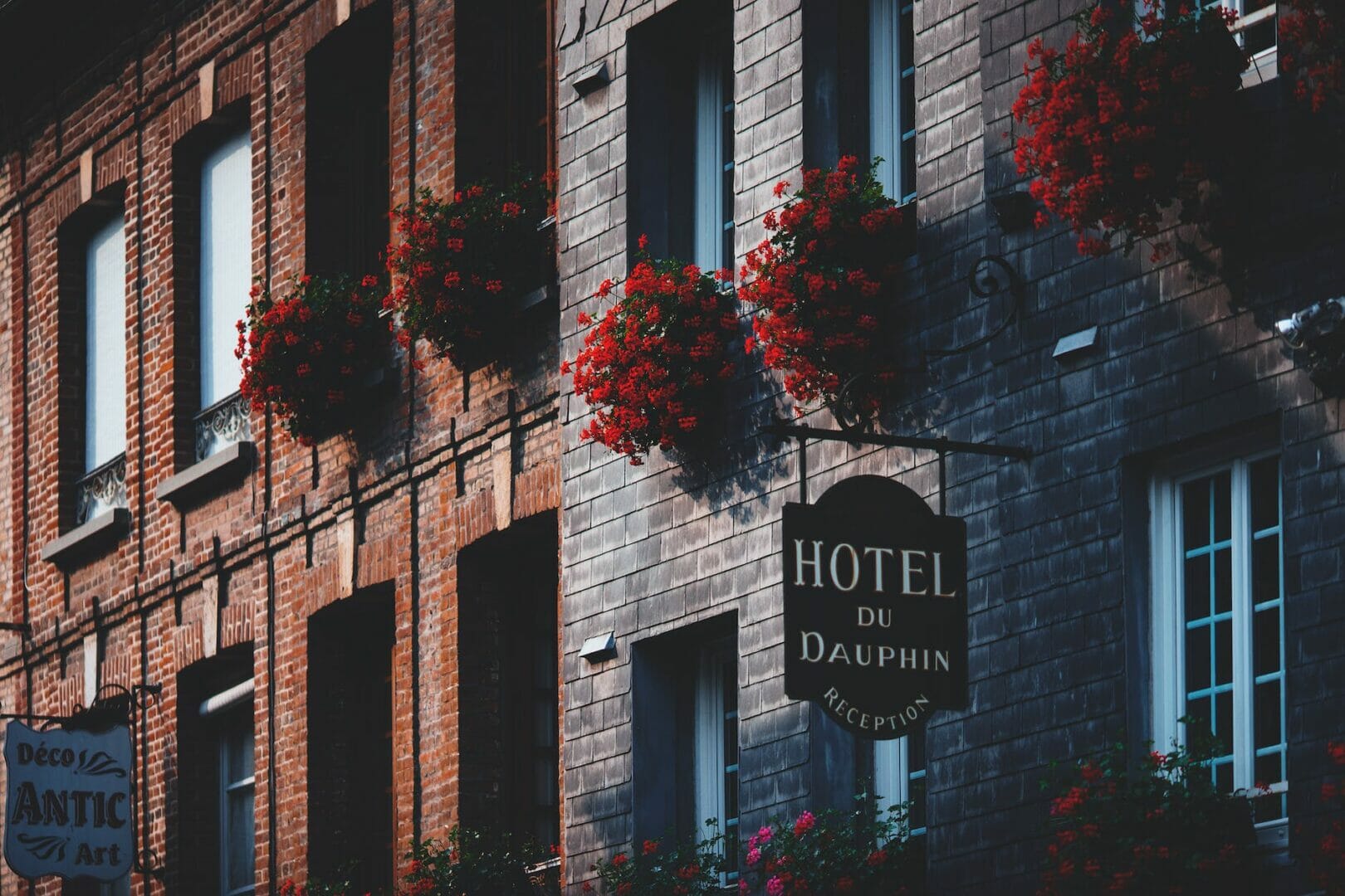 facade of modern masonry building decorated with red flowers - Europe Travel Tips